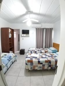 a hotel room with two beds and a tv at Hotel Pousada Sinos in São Leopoldo