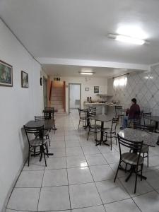a restaurant with tables and chairs and a man sitting at a counter at Hotel Pousada Sinos in São Leopoldo
