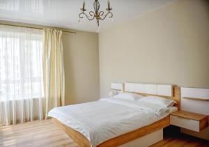 a bedroom with a bed with a chandelier and a window at Apart Reserve Sloboda Klassik in Ivano-Frankivsk