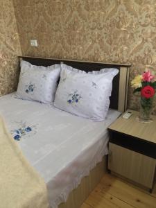 Una cama con almohadas blancas y un jarrón con flores. en HOTEL JULIA Akhaltsikhe en Akhaltsikhe