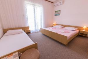 a room with two beds and a chair in it at Rooms Nada in Senj
