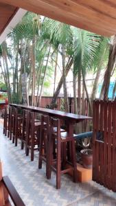 a row of wooden tables and chairs in front of palm trees at DownTown Backpackers Hostel in Luang Prabang