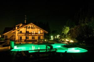 a swimming pool at night in front of a house at Holidays Dolomiti Apartment Resort in Carisolo