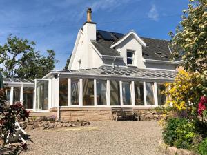 a white house with a conservatory with windows at Balmillig B&B in Helensburgh