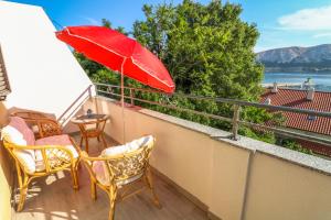 a patio with a red umbrella and chairs on a balcony at Apartments Andrea in Baška