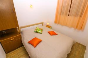 a bedroom with a bed with orange pillows on it at Apartments Andrea in Baška