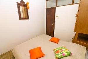 a small room with a bed with orange pillows on it at Apartments Andrea in Baška