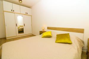 a bedroom with a white bed with two yellow pillows at Apartments Andrea in Baška