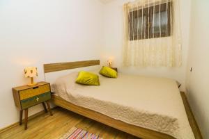 a bedroom with a bed with yellow pillows and a window at Apartments Andrea in Baška