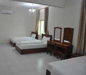 a hotel room with two beds and a desk at Al Sqlawi Hotel Apartments in Sur