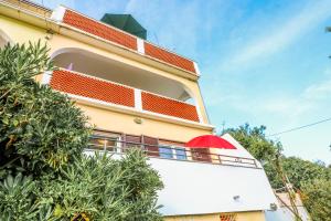 a building with a red umbrella on a balcony at Apartments Andrea in Baška