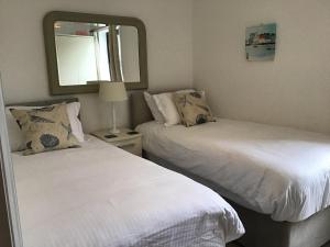 two beds in a small room with a mirror at Sunnyside Cottage in Crantock