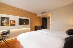 a hotel room with a white bed and a chair at Mercure Rouen Centre Champ de Mars in Rouen