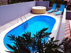 a swimming pool with blue chairs and a spa at Villa Veronique in Dramalj