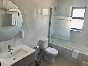 bagno con servizi igienici, lavandino e specchio di Alojamento Restaurante Dom Dinis a Vila Nova de Poiares