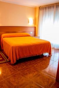 a bedroom with a bed with an orange blanket at Hotel Mabú in Ourense