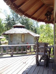 a wooden deck with a bench and a hut at Malibu Beach Bungalows in Chaloklum