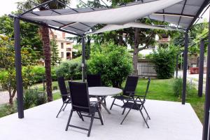 patio con tavolo e sedie sotto un baldacchino bianco di Villa UMA a Izola