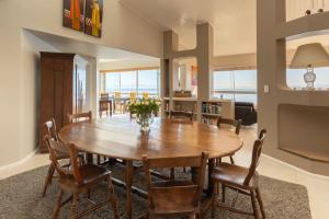 uma sala de jantar com uma mesa de madeira e cadeiras em Celtic Manor Boutique Guest House em Gordonʼs Bay