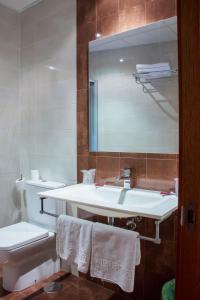 a bathroom with a sink and a toilet and a mirror at Hotel Mabú in Ourense