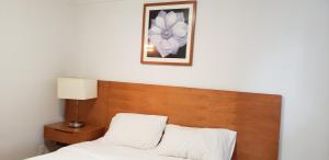 a bed with a wooden headboard and a picture on the wall at Niagara Inn in Niagara Falls