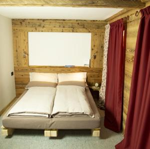 a bed in a room with a window and red curtains at B&B Cedavécia in Comèlico Superiore