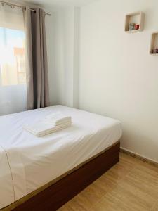een slaapkamer met een bed met witte lakens en een raam bij Apartment in Torrevieja