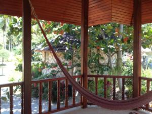 a hammock on a porch with a tree at Malibu Beach Bungalows in Chaloklum
