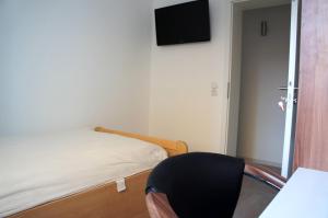 a bedroom with a bed and a black chair at Forsthaus Appartements in Braunschweig
