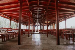 um pavilhão com mesas e cadeiras de madeira num edifício em Hotel-Restaurant Milenium em Salonta