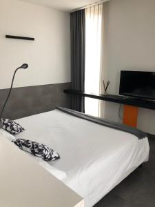 Cama blanca en habitación con TV en Parco Paglia Home, en Chieti