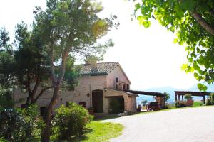 an old stone house with a tree and a driveway at Agriturismo Villa Rosetta in San Severino Marche
