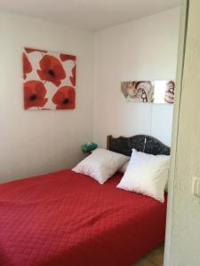 1 dormitorio con 1 cama roja y 2 almohadas en Agréable F3 sur Carnon-plage à 10 mn de Montpellier, en Carnon-Plage