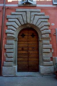 a wooden door in a building with an arch at Palazzo San Florido in Città di Castello