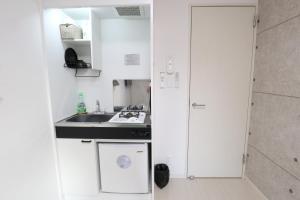 a small kitchen with white cabinets and a sink at Tokyo Sakura hotel in Tokyo