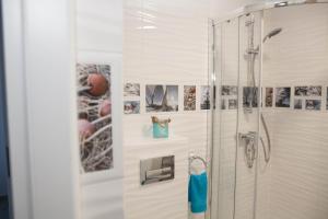 a bathroom with a shower with pictures on the wall at Apartament nad jeziorem Nidzkim in Ruciane-Nida +30 photos