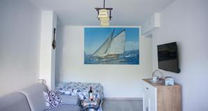 a living room with a couch and a sail boat on the wall at Apartament nad jeziorem Nidzkim in Ruciane-Nida