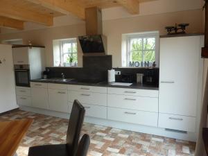 a kitchen with white cabinets and a black counter top at Ferienwohnung Landtraum in Klanxbüll