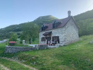 a small stone building with people sitting outside of it at Lovcen Holiday Home in Cetinje