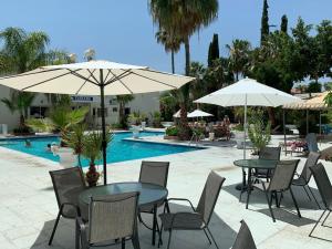 a table and chairs with umbrellas and a pool at Tasiana Star Complex in Limassol