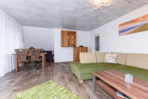 a living room with a green couch and a table at Ferienwohnung Haus zum Seehund mit Pool und Frühstücksoption in Bensersiel