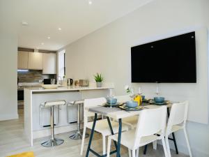 a kitchen and dining room with a table and chairs at Beautiful AlumPointe Apartment - 400m to the beach in Bournemouth