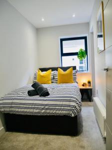 a bedroom with a large bed with yellow pillows at Beautiful AlumPointe Apartment - 400m to the beach in Bournemouth