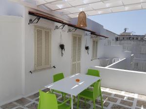 a white table and green chairs on a balcony at Residence Orsa Minore in Gallipoli