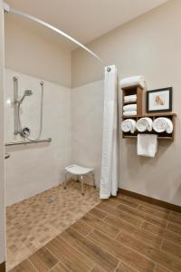 a bathroom with a shower and a bench and towels at GrandStay Hotel & Suites in Sisters