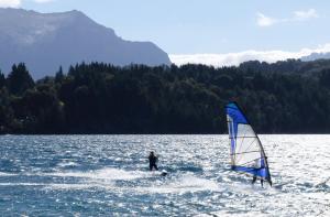 a person windsurfing on a lake with a sail at Casa de campo con costa de lago in San Carlos de Bariloche