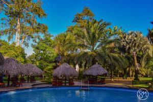 una piscina con sombrillas, mesas y palmeras en De Plantage en Tamanredjo