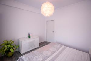 a white bedroom with a bed and a chandelier at Nairi Apartment in Mamaia Nord