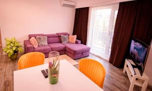 a living room with a purple couch and a table at Nairi Apartment in Mamaia Nord