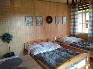 two beds in a room with wooden walls at Arena White Houses in Okuninka